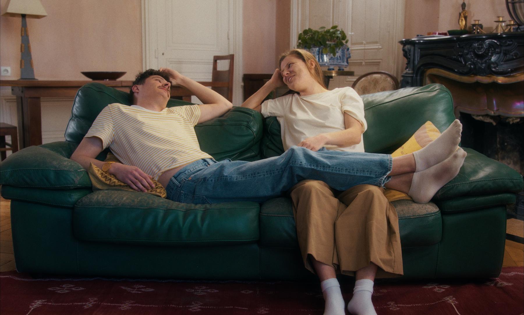 Photogramme du film Un Ange Aimé : un couple complice sur le canapé vert, dans le salon.