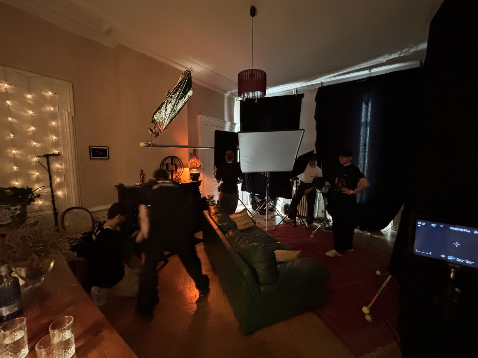 Sur le plateau : préparation d'une scène de soirée, guirlande lumineuse et drapeaux noirs.