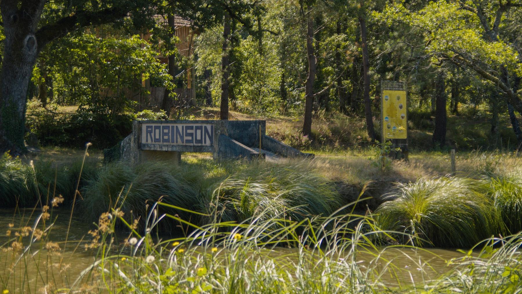 Repérage : un ponton de béton marqué Robinson au bord d'un plan d'eau, dans la verdure.