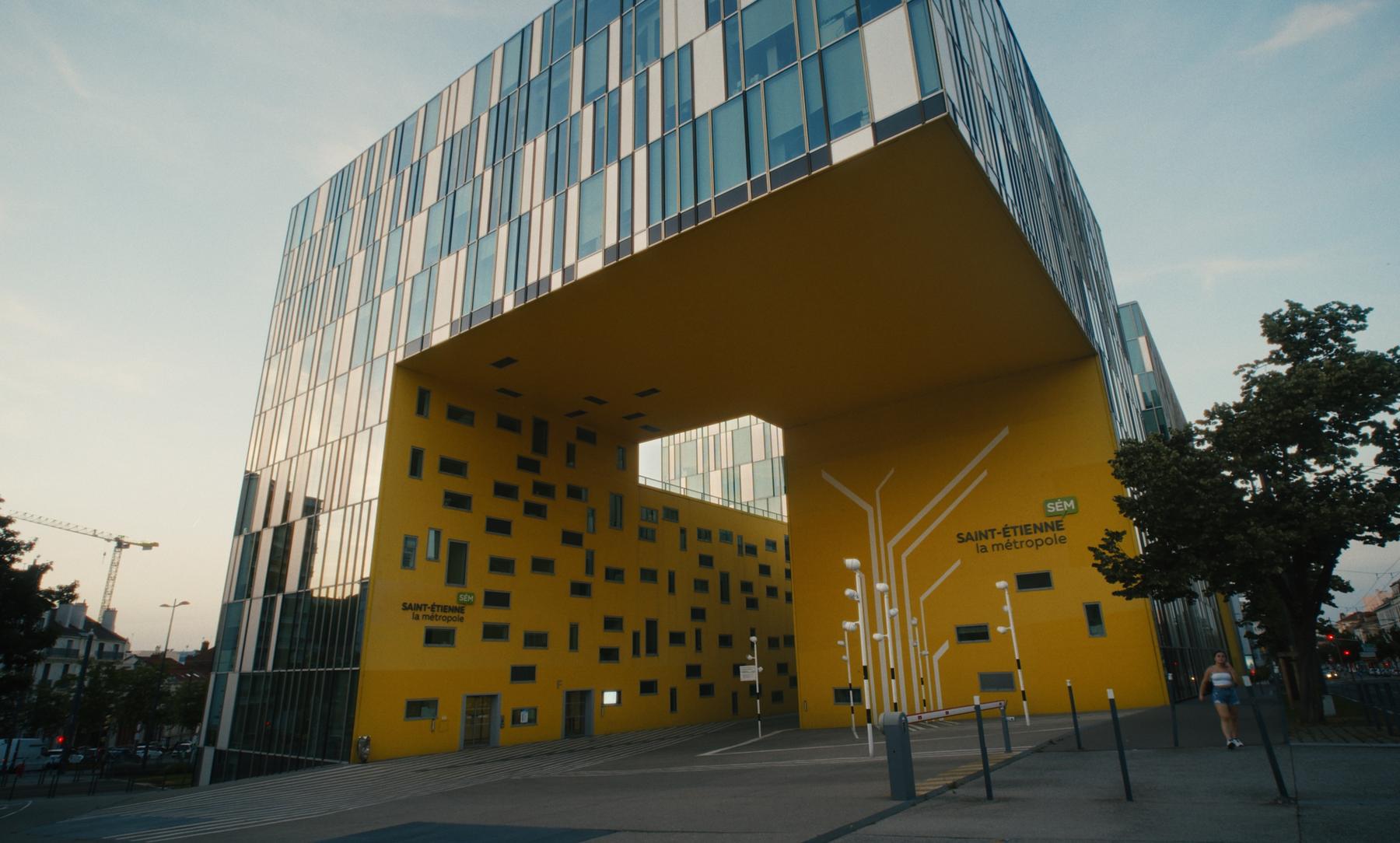 Photogramme : le bâtiment jaune de Saint-Étienne Métropole au crépuscule.