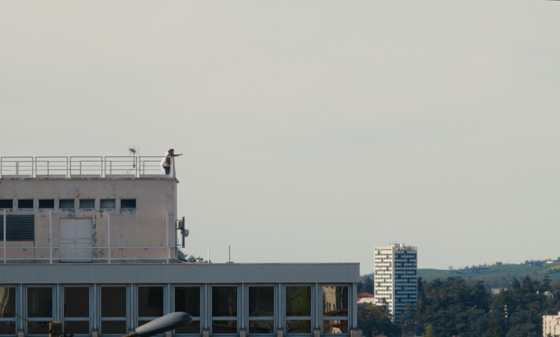 Photogramme : sur un toit, une silhouette pointe l'horizon du doigt.